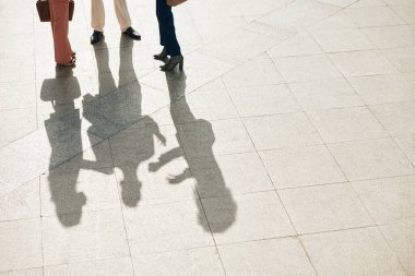 İş adamları dışarıda fayans döşemesinde duruyorlar ve şu anda üzerinde çalıştıkları projeden bahsediyorlar.