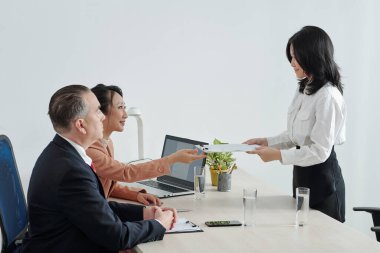 Gülümseyen genç başvuru sahibi, iş görüşmesinden önce İK müdürü ve şirket CEO 'suna yazılı müfredat vitae veriyor.