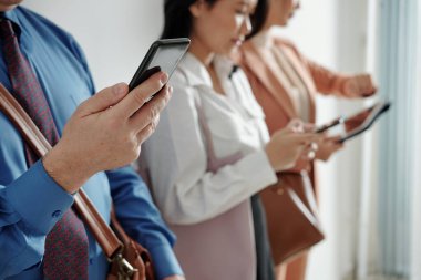 Ofiste iş görüşmesi sırasında telefonunu kontrol eden olgun bir adamın elleri, seçici bir odaklanma.