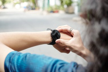 Yolda duran ve çalıştıktan sonra aktivite takip cihazını kontrol eden tanınmamış bir adamın yakın çekimi.