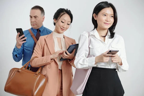 Smiling Pensive Young Businesswoman Holding Smartphone Her Colleagues Standing Answering — Stock Photo, Image