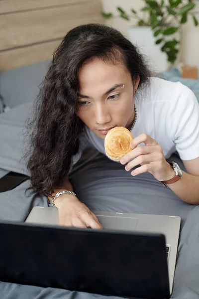 Jovem Freelancer Asiático Sério Com Cabelo Comprido Deitado Cama Comendo — Fotografia de Stock