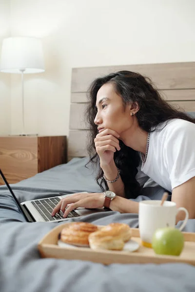 Düşünceli Genç Vietnamlı Internet Yöneticisi Uzun Saçlı Yatakta Kahvaltı Tepsisi — Stok fotoğraf