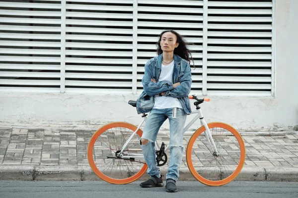 Серьезный Уверенный Молодой Азиатский Велосипедист Джинсовой Одежде Стоит Скрещенными Руками — стоковое фото