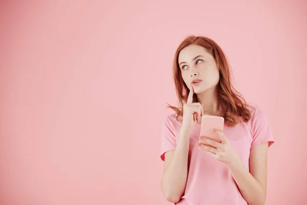 スマートフォンを手に テキストメッセージへの答えを検索し 考えるとかなり若い赤髪の女性の肖像画 — ストック写真
