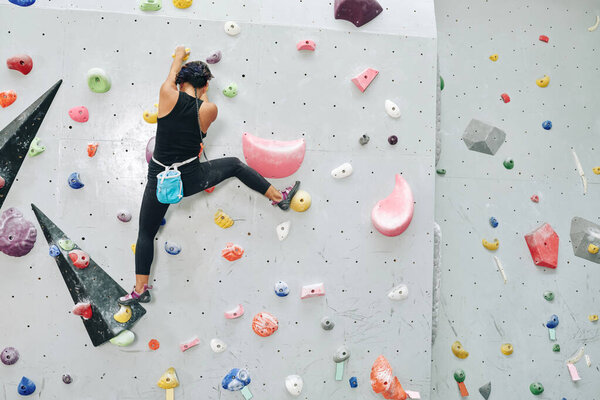 Fit Athlete Climbing up Bouldering Wall