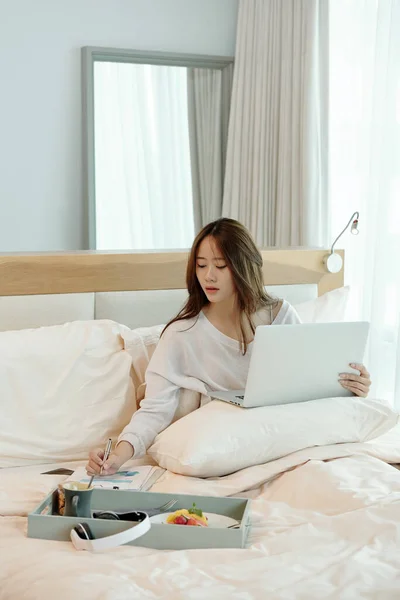 Jeune femme travaillant au lit — Photo