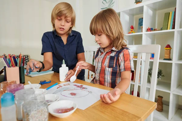 Bruder klebt Glitzer auf Papier — Stockfoto