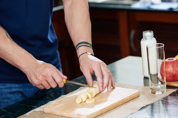 Hombre muscular cortando plátano fresco — Foto de Stock