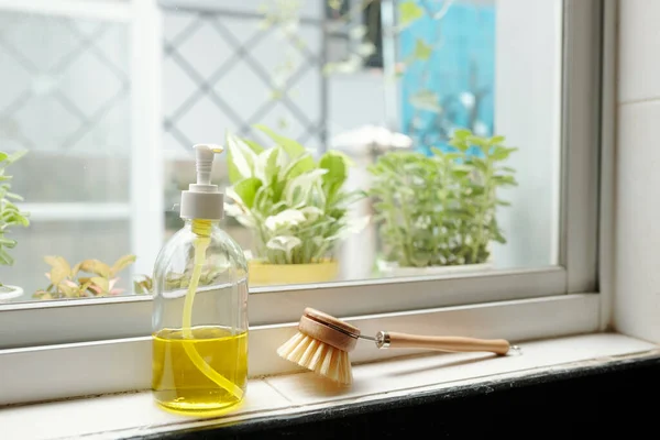 厨房的窗台上放一壶黄色的肥皂和刷子 — 图库照片