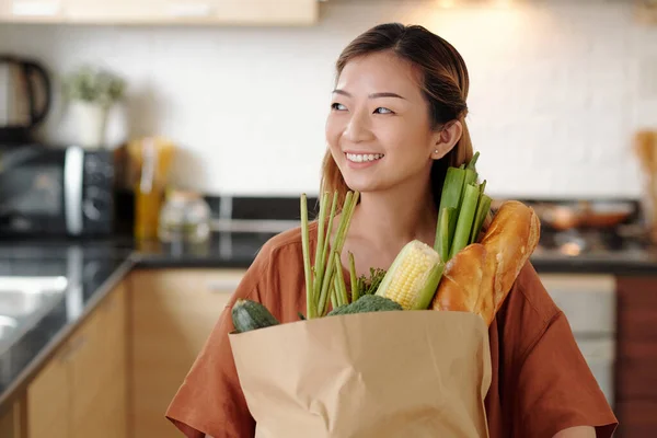 幸福漂亮的年轻女子站在厨房里 提着面包和蔬菜等新鲜食品纸袋的画像 — 图库照片