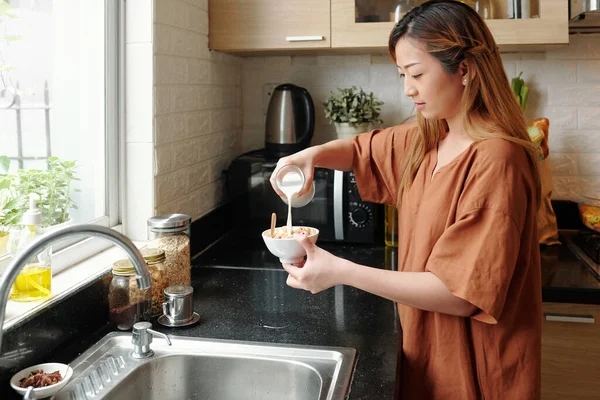 Mooie vrouw gieten melk in schaal — Stockfoto