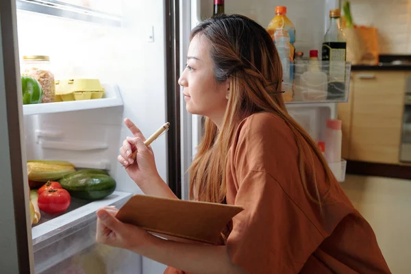 Kvinnlig kontroll av livsmedel i kylskåp — Stockfoto