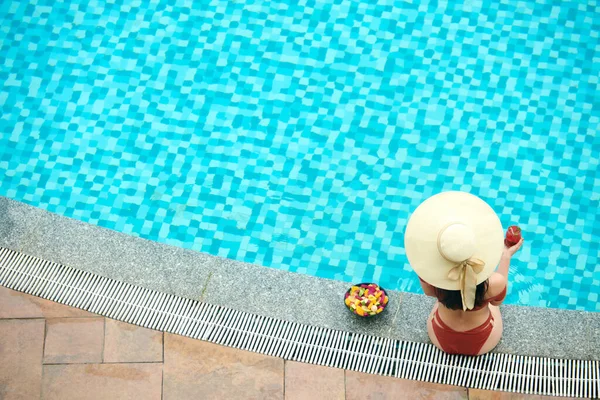 Femme en chapeau assis près de la piscine — Photo