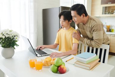 Baba, Oğul 'a ödevlerinde yardım ediyor.