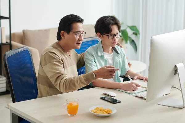 Hombre ayudando a hijo con hacer la tarea —  Fotos de Stock