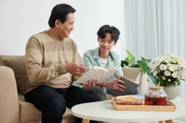 Adam oğluna kitap gösteriyor.