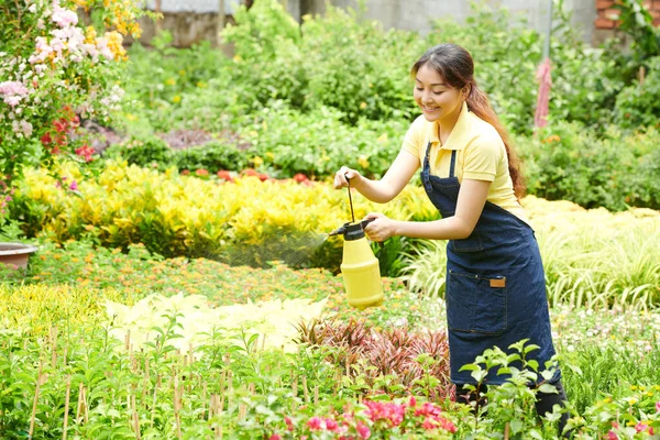 Gartencenter-Mitarbeiter sprüht Blumen — Stockfoto