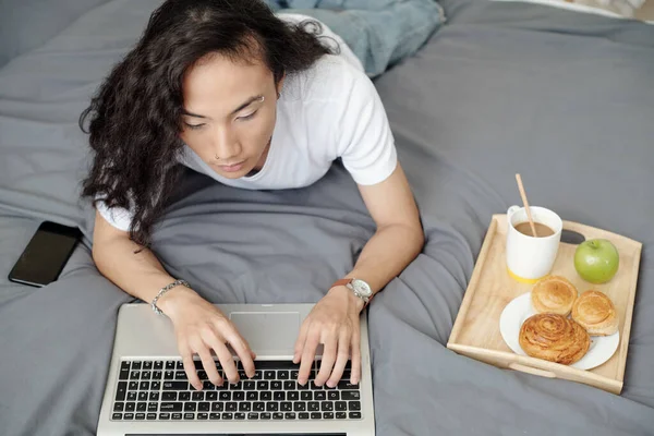 Homem comendo café da manhã na cama — Fotografia de Stock