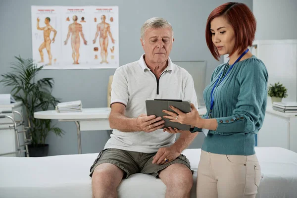 Fisioterapeuta hablando con el paciente mayor — Foto de Stock