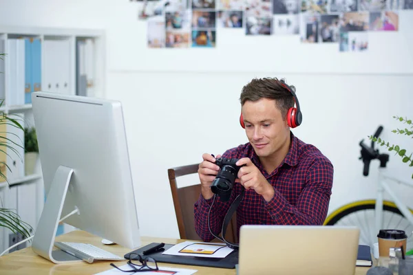 Usmívající se fotograf sedí na kancelářském stole — Stock fotografie