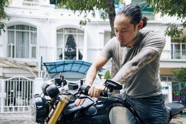 Genç adam motosikleti siliyor.