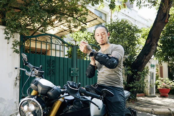 Motociclista poniéndose la almohadilla protectora del antebrazo — Foto de Stock