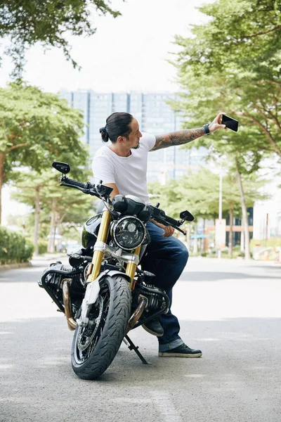 Homem fotografando ao lado da motocicleta — Fotografia de Stock