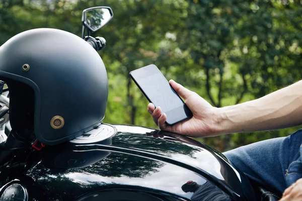 Motorradfahrer checkt App auf Smartphone — Stockfoto