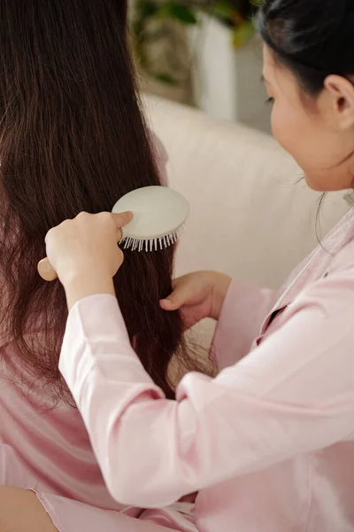Kobieta pozwalając siostrze szczotkować włosy — Zdjęcie stockowe