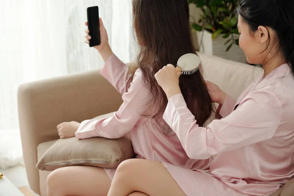 Frau bürstet Freundin wirres Haar — Stockfoto