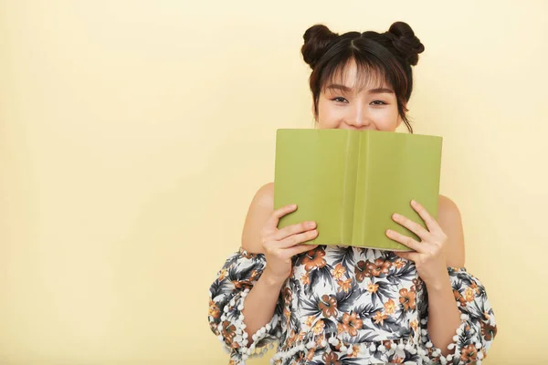 Vrouw verbergen glimlach achter geopende boek — Stockfoto