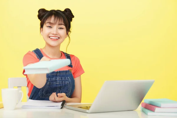 Sorrindo Jovem mulher dando livro — Fotografia de Stock