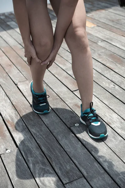 Молода жінка, яка торкається болючої ноги — стокове фото