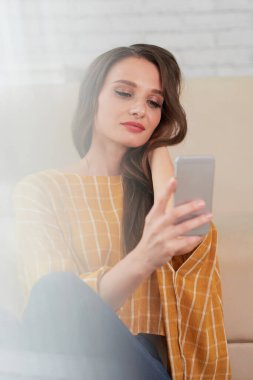 Esmer kadın telefonda selfie çekiyor.