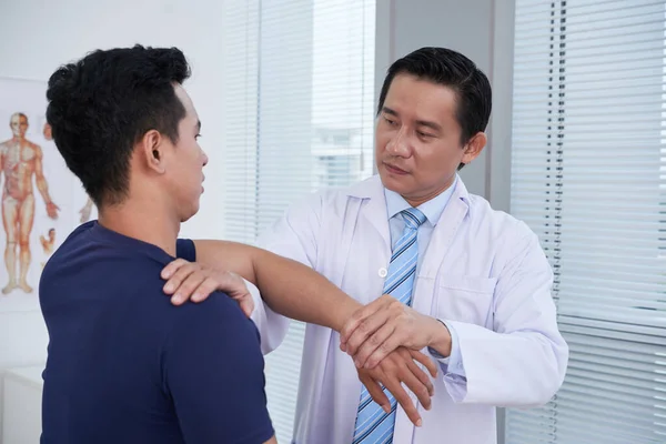 Artsen die sportman onderzoeken in de kliniek — Stockfoto