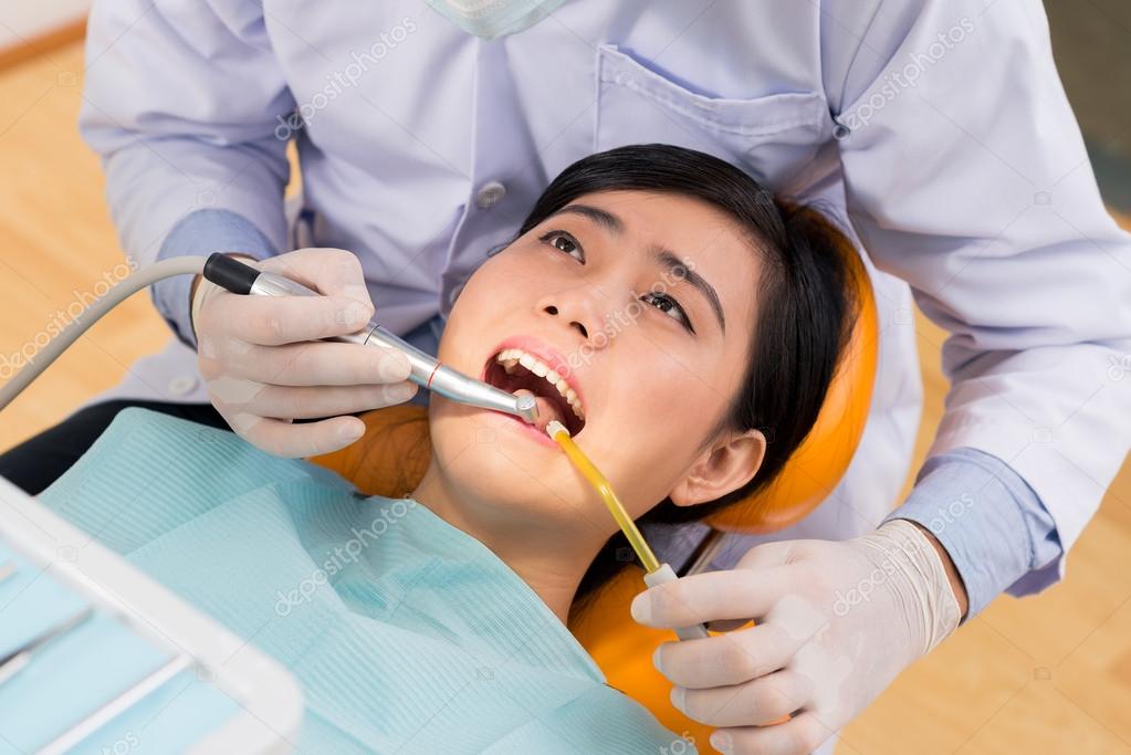 Dentist drilling tooth of a young woman — Stock Photo © DragonImages