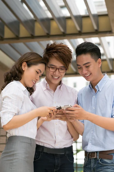 Азиатские друзья, занятые смартфонами — стоковое фото