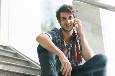 Genç adam telefonda konuşuyor.