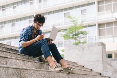 dizüstü bilgisayar ile merdivenlerde oturan adam