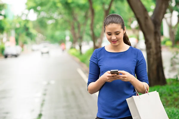 Vrouw met papieren zakken texting — Stockfoto