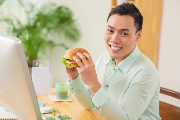 Vietnamesischer Geschäftsmann isst Hamburger — Stockfoto