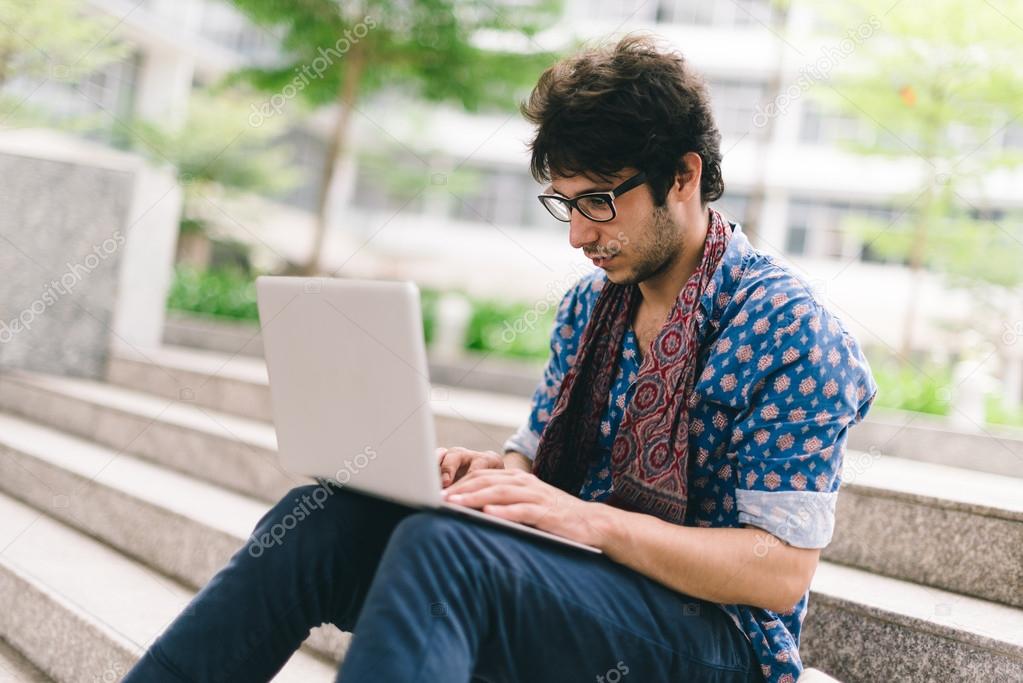 Hipster blogging while sitting on the steps