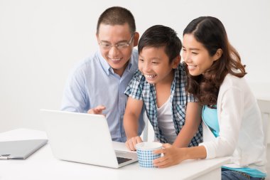 Asya ailesi dizüstü bilgisayarda bir şey izliyor