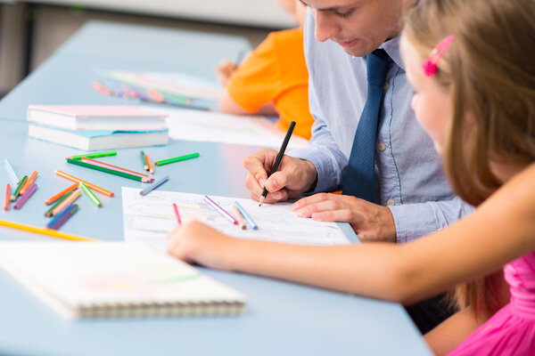 Teacher helping schoolgirl to draw a picture
