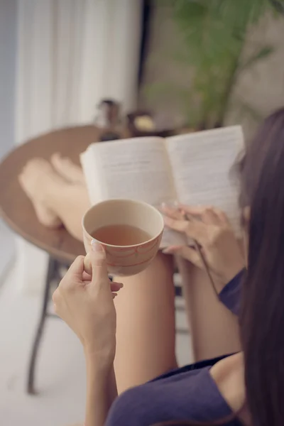 Γυναίκα πίνοντας τσάι διαβάζοντας ένα βιβλίο — Φωτογραφία Αρχείου