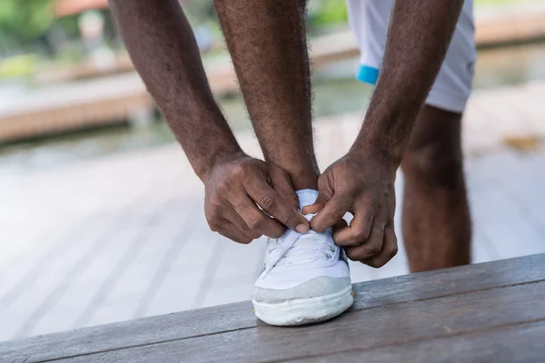Sportsman allacciatura lacci sulle sue scarpe da allenamento — Foto Stock