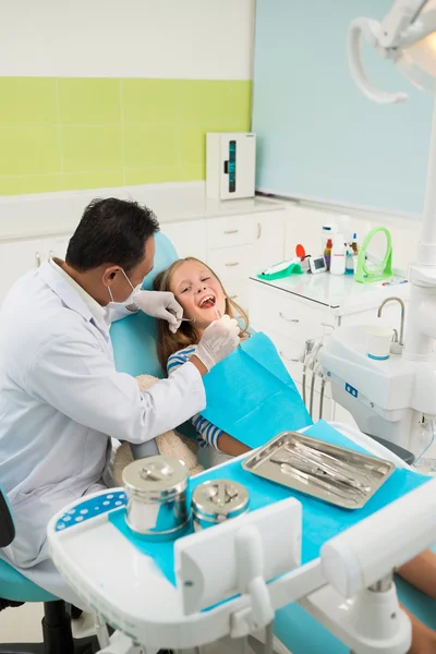 Läkaren undersöker tänderna av en ung flicka — Stockfoto