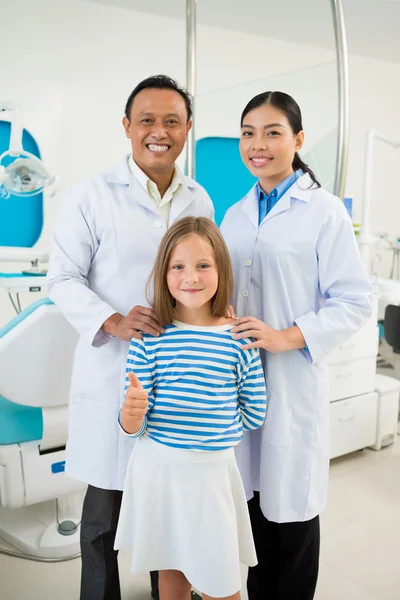 Mädchen zeigt Daumen hoch mit Zahnarztteam — Stockfoto