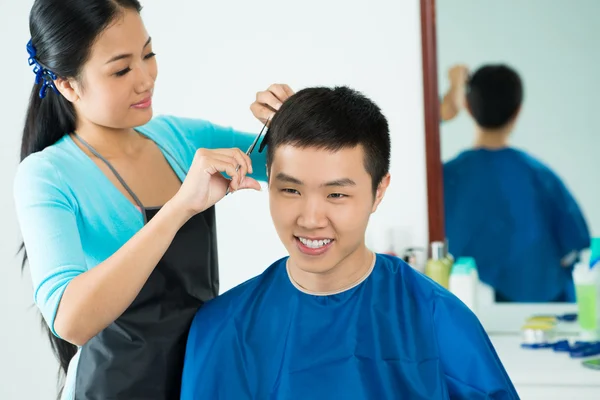 Kvinnlig frisör klippa hår av manlig klient — Stockfoto